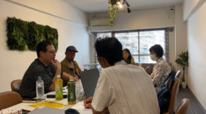 リアルミーティングで中野和幸が徳ある資本の理念のもと、リアルでWeb3やAIトレードツールSageMaster（セージマスター）の設定について話している写真。