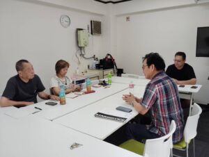 徳ある資本の理念に賛同した仲間がリアルミーティングで、リアルでWeb3やAIトレードツールSageMaster（セージマスター）の設定について話している写真。